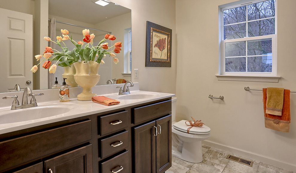 Inspiration for a mid-sized traditional master bathroom in Other with dark wood cabinets, an alcove shower, a two-piece toilet, beige walls, vinyl floors, an integrated sink, marble benchtops and a shower curtain.