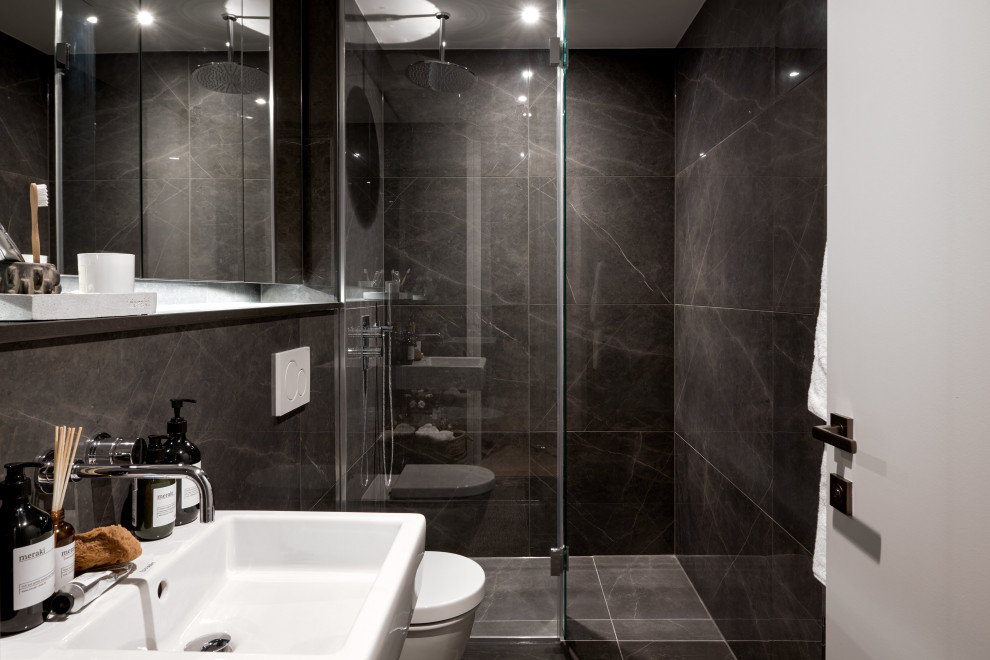 This is an example of a small modern master bathroom in Hampshire with an open shower, a wall-mount toilet, black tile, marble, black walls, marble floors, a wall-mount sink, marble benchtops, black floor, an open shower and black benchtops.