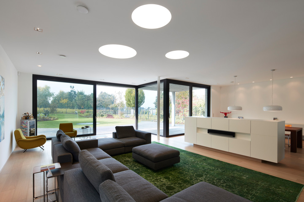 Large midcentury open concept living room in Dusseldorf with white walls, light hardwood floors and brown floor.