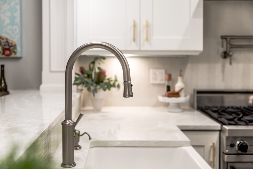 Inspiration for a mid-sized transitional u-shaped dark wood floor and brown floor eat-in kitchen remodel in Chicago with a farmhouse sink, shaker cabinets, white cabinets, quartz countertops, gray backsplash, glass tile backsplash, stainless steel appliances, a peninsula and gray countertops