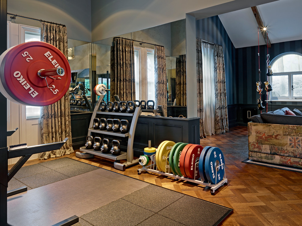 Photo of an eclectic home gym in London with blue walls and medium hardwood floors.