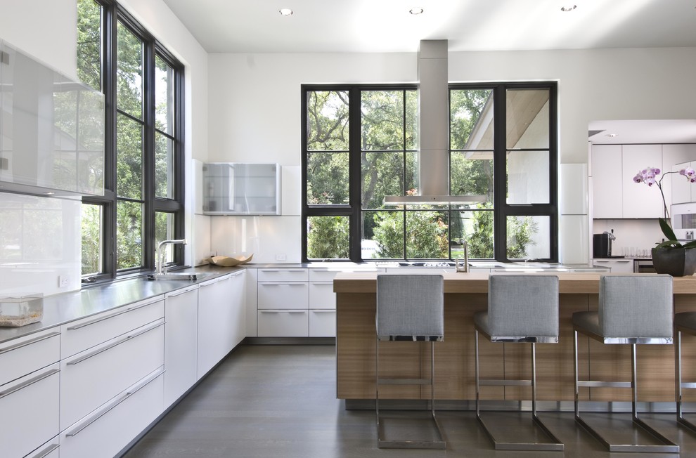 Photo of a transitional kitchen in Dallas with flat-panel cabinets, white cabinets, white splashback, glass sheet splashback and stainless steel appliances.
