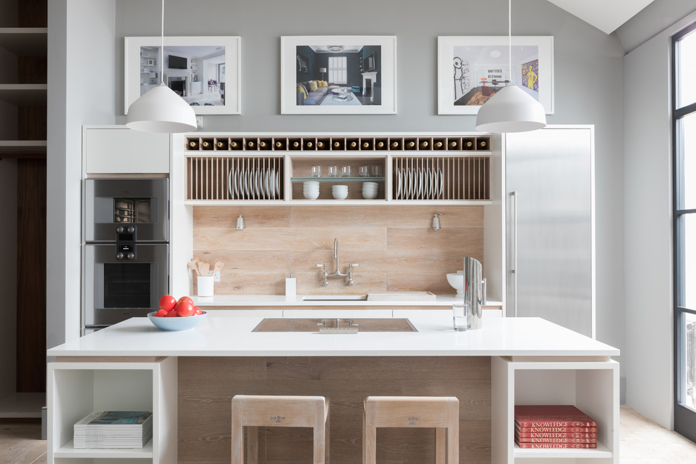 Photo of a small contemporary single-wall eat-in kitchen in London with an undermount sink, flat-panel cabinets, white cabinets, quartzite benchtops, beige splashback, timber splashback, stainless steel appliances, light hardwood floors and a peninsula.