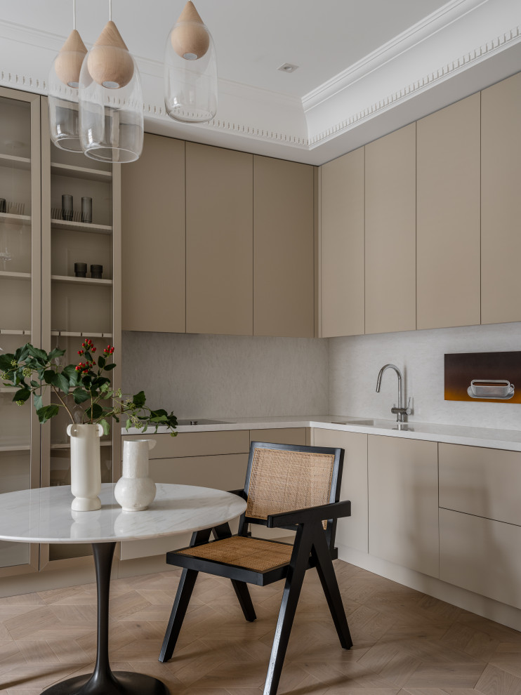 Design ideas for a contemporary l-shaped eat-in kitchen in Moscow with flat-panel cabinets, beige cabinets, solid surface benchtops, white splashback, white benchtop, light hardwood floors and beige floor.
