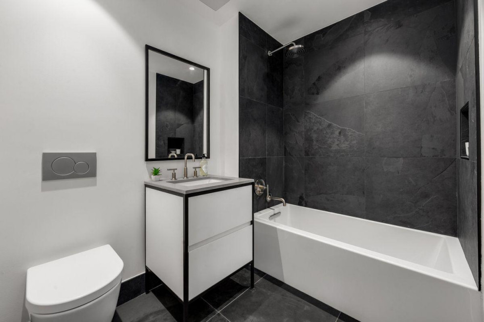 Photo of a mid-sized contemporary 3/4 bathroom in New York with furniture-like cabinets, white cabinets, a hot tub, a shower/bathtub combo, a one-piece toilet, black and white tile, white walls, ceramic floors, an integrated sink, marble benchtops, black floor, an open shower, grey benchtops, an enclosed toilet, a single vanity and a freestanding vanity.