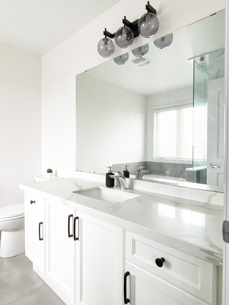 Пример оригинального дизайна: главная ванная комната среднего размера в стиле неоклассика (современная классика) с фасадами в стиле шейкер, белыми фасадами, унитазом-моноблоком, белыми стенами, полом из керамогранита, столешницей из искусственного кварца, серым полом, нишей, тумбой под одну раковину, напольной тумбой, накладной ванной, угловым душем, серой плиткой, врезной раковиной, душем с распашными дверями и белой столешницей