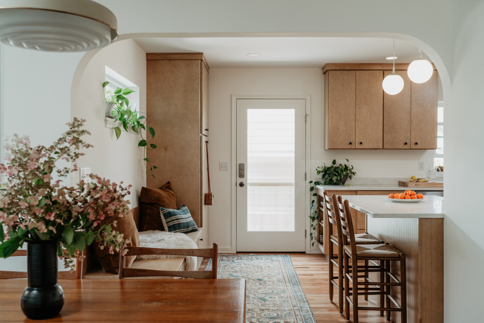 Inspiration for a mid-sized 1960s l-shaped medium tone wood floor kitchen pantry remodel in Detroit with an undermount sink, flat-panel cabinets, light wood cabinets, quartz countertops, white backsplash, quartz backsplash, stainless steel appliances, a peninsula and white countertops