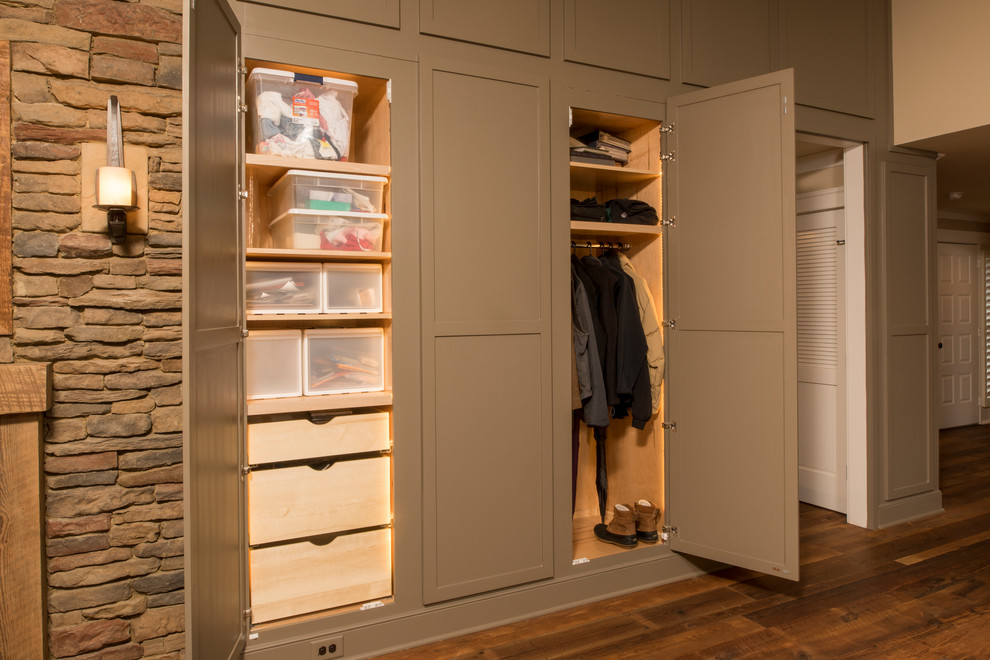 Photo of a mid-sized transitional gender-neutral built-in wardrobe in Raleigh with recessed-panel cabinets, medium hardwood floors, brown floor and green cabinets.