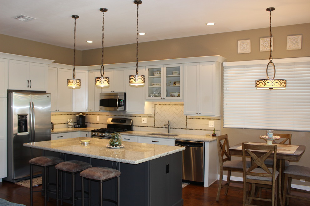 Mid-sized transitional l-shaped dark wood floor and brown floor open concept kitchen photo in Phoenix with an undermount sink, shaker cabinets, white cabinets, granite countertops, white backsplash, subway tile backsplash, stainless steel appliances and an island