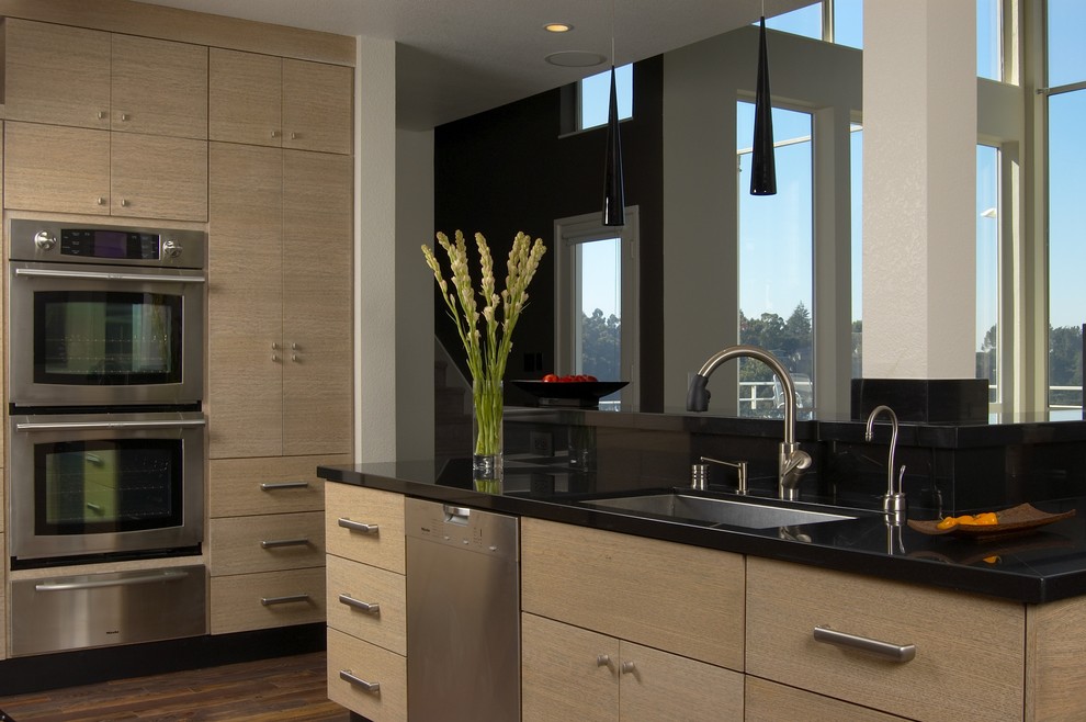This is an example of a contemporary kitchen in San Francisco with flat-panel cabinets, an undermount sink, light wood cabinets, granite benchtops and stainless steel appliances.