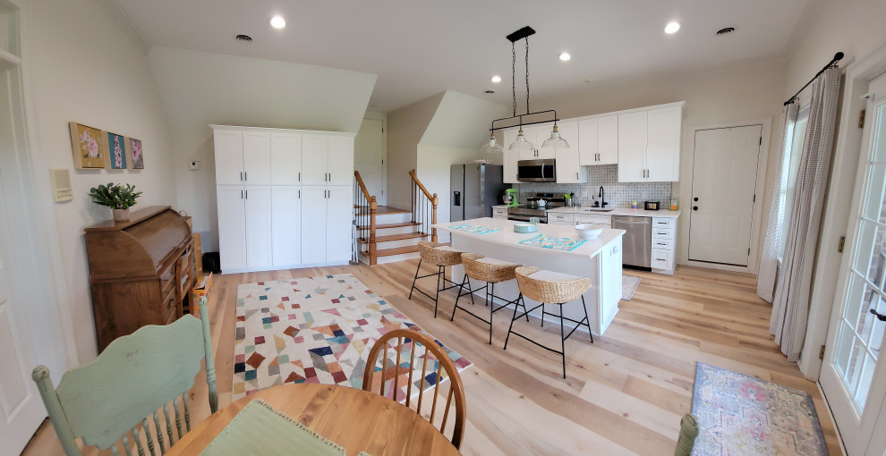 Foto di una sala da pranzo aperta verso la cucina minimal con pareti bianche, pavimento in vinile e pavimento marrone