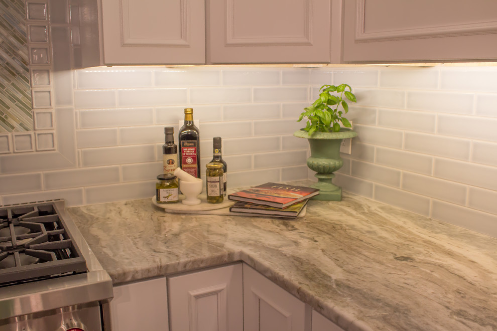 Example of a mid-sized classic l-shaped dark wood floor eat-in kitchen design in Providence with recessed-panel cabinets, white cabinets, gray backsplash, subway tile backsplash, stainless steel appliances and an island