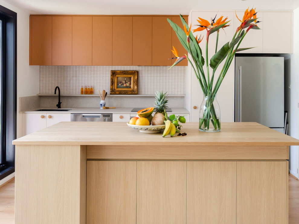 Design ideas for a mid-sized eclectic galley eat-in kitchen in Melbourne with an undermount sink, flat-panel cabinets, pink cabinets, wood benchtops, white splashback, mosaic tile splashback, stainless steel appliances, laminate floors, with island, yellow floor and yellow benchtop.