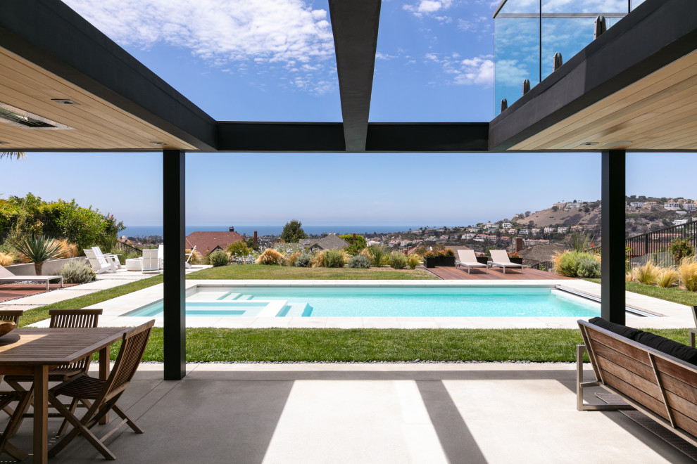 Inspiration for a mid-sized modern backyard rectangular pool in Orange County with a water feature and concrete slab.