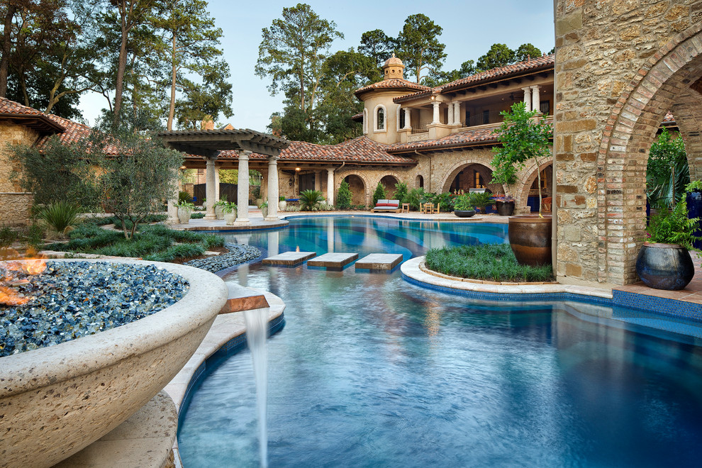 Expansive mediterranean backyard custom-shaped pool in Houston with a water feature.