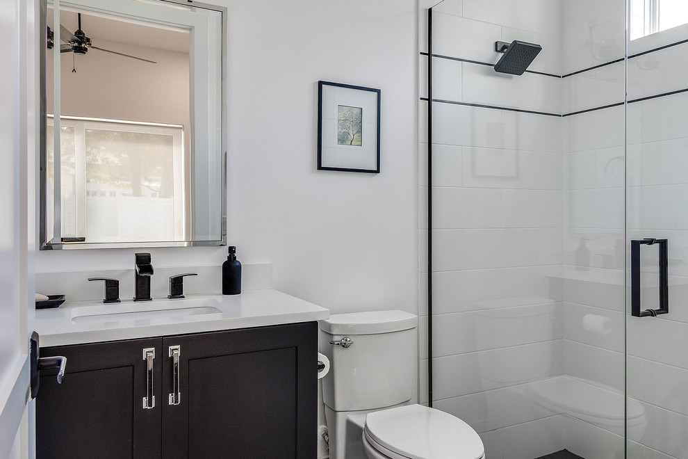 This is an example of a mid-sized transitional bathroom in Orlando with shaker cabinets, dark wood cabinets, white tile, marble benchtops, white benchtops, a curbless shower, a two-piece toilet, ceramic tile, white walls, mosaic tile floors, an undermount sink, multi-coloured floor and a hinged shower door.