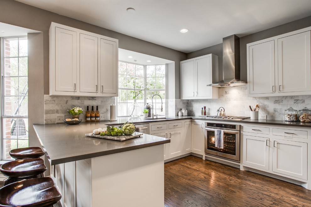 Design ideas for a transitional u-shaped kitchen in Dallas with a single-bowl sink, shaker cabinets, white cabinets, white splashback and stainless steel appliances.