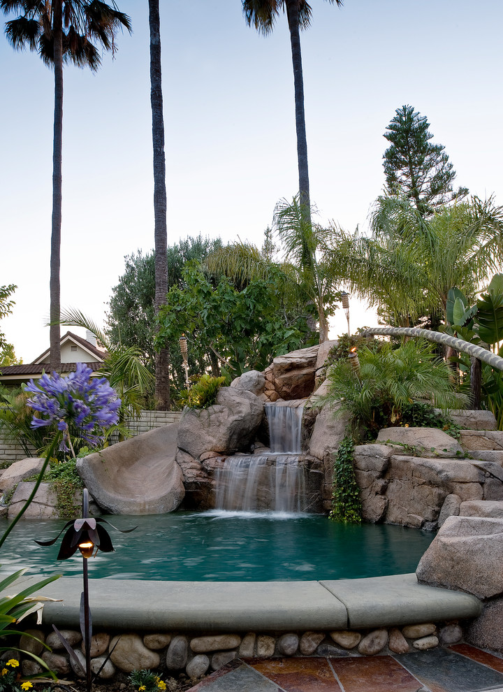 Photo of a tropical natural pool in Orange County with a water slide.
