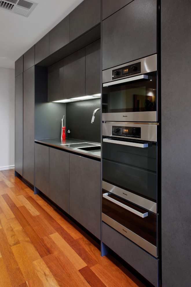 Design ideas for a mid-sized contemporary eat-in kitchen in Perth with an undermount sink, quartz benchtops, grey splashback, glass sheet splashback, stainless steel appliances, medium hardwood floors and with island.