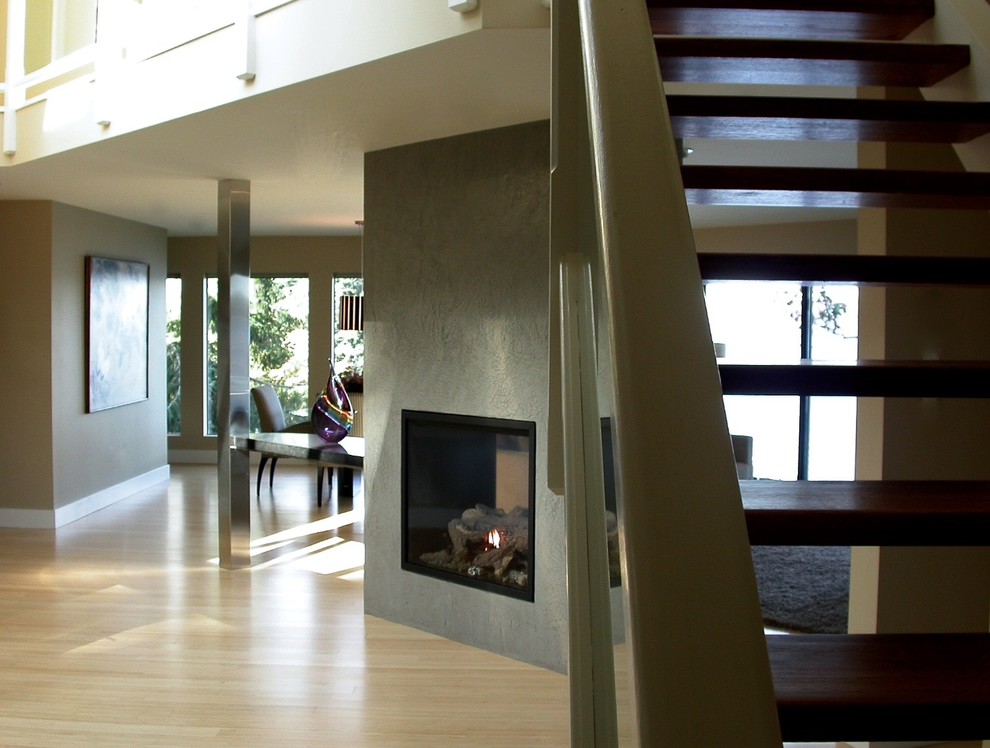 Photo of a mid-sized contemporary open concept living room in Vancouver with beige walls, light hardwood floors, a two-sided fireplace and a concrete fireplace surround.