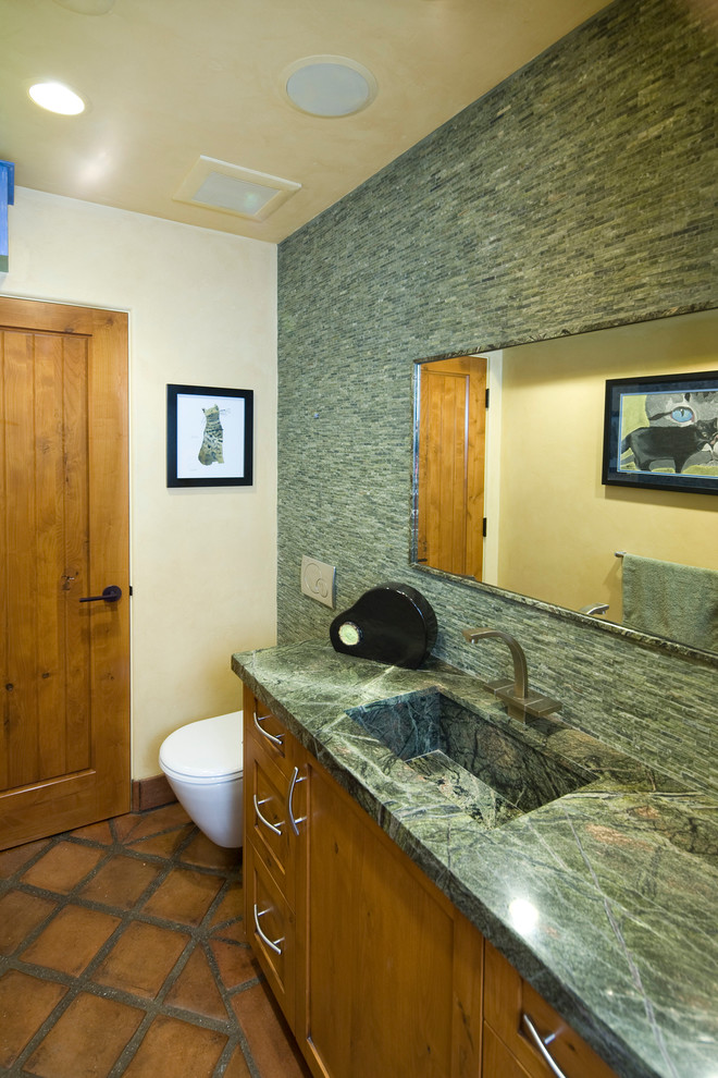 This is an example of an eclectic bathroom in Santa Barbara with an integrated sink, shaker cabinets, medium wood cabinets, a bidet, green tile, stone tile, granite benchtops, beige walls and terra-cotta floors.