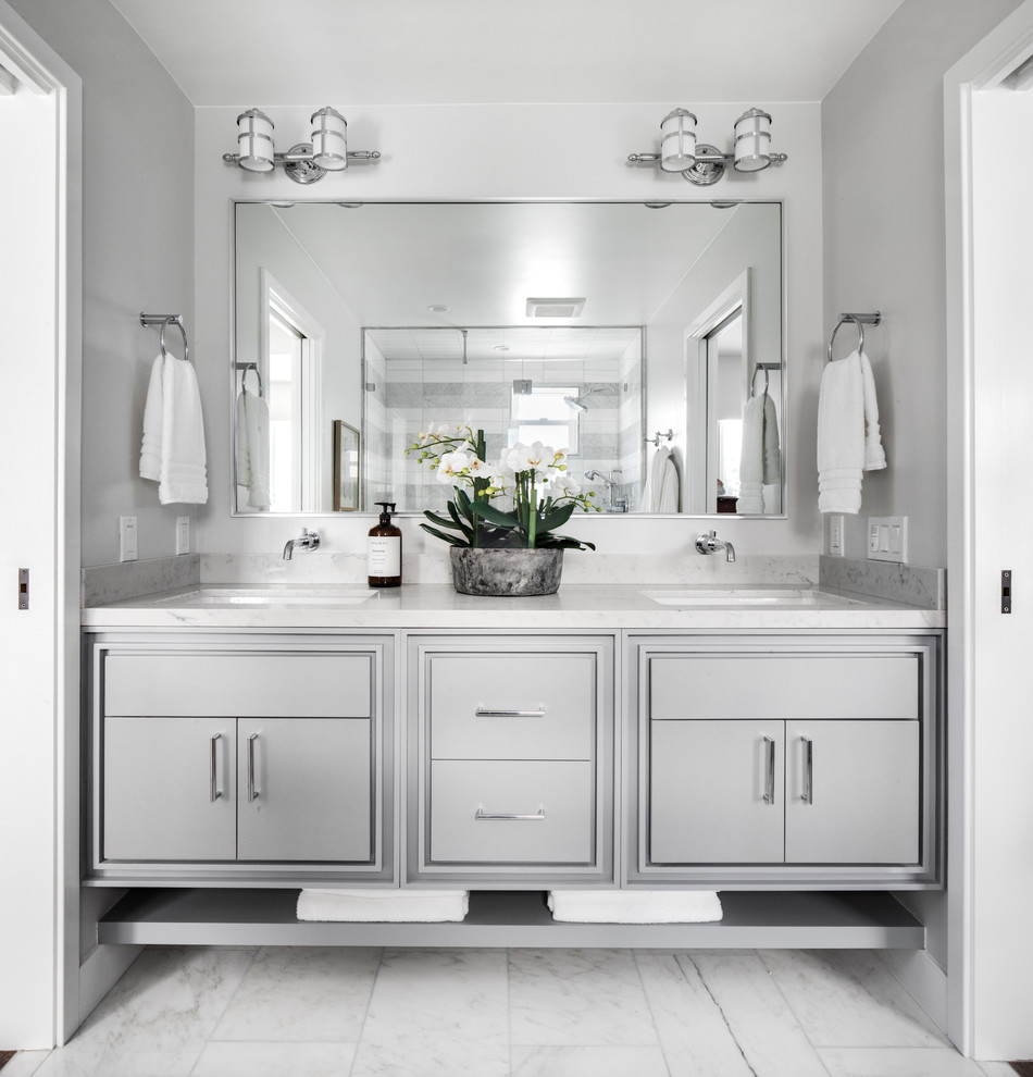 Design ideas for a mid-sized beach style 3/4 bathroom in Los Angeles with shaker cabinets, grey cabinets, an alcove shower, a one-piece toilet, white tile, marble, grey walls, marble floors, an undermount sink, engineered quartz benchtops, white floor, a hinged shower door and white benchtops.