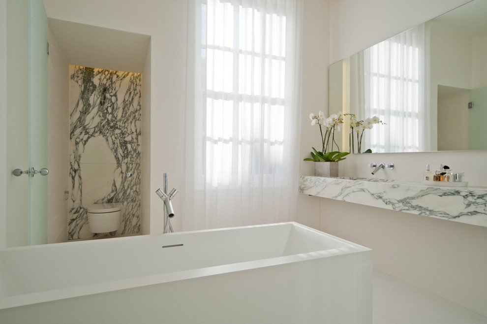 Inspiration for a mid-sized contemporary master bathroom in London with white cabinets, marble benchtops, a one-piece toilet, white walls, marble floors, an integrated sink and marble.