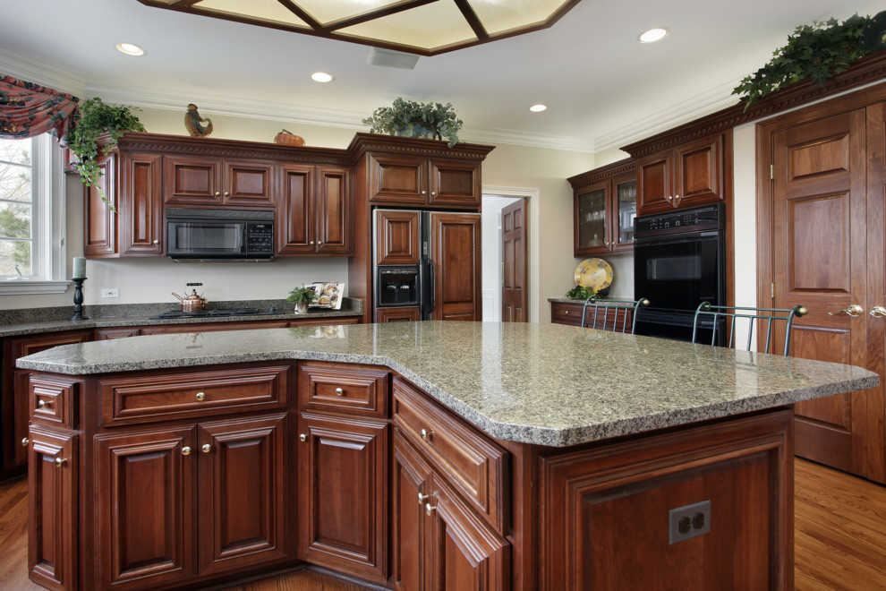 Example of a classic u-shaped eat-in kitchen design in Philadelphia with an undermount sink, raised-panel cabinets, medium tone wood cabinets, granite countertops, gray backsplash, stone slab backsplash and black appliances
