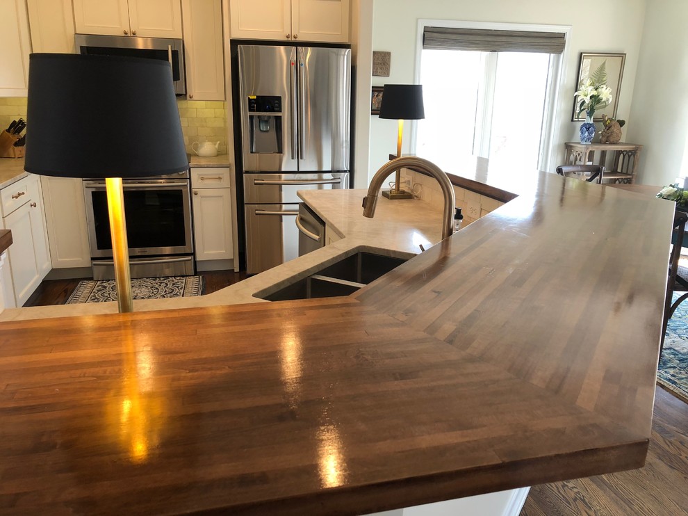 Example of a large transitional dark wood floor and brown floor open concept kitchen design in Omaha with an undermount sink, recessed-panel cabinets, beige cabinets, quartz countertops, beige backsplash, stone tile backsplash, stainless steel appliances, an island and beige countertops