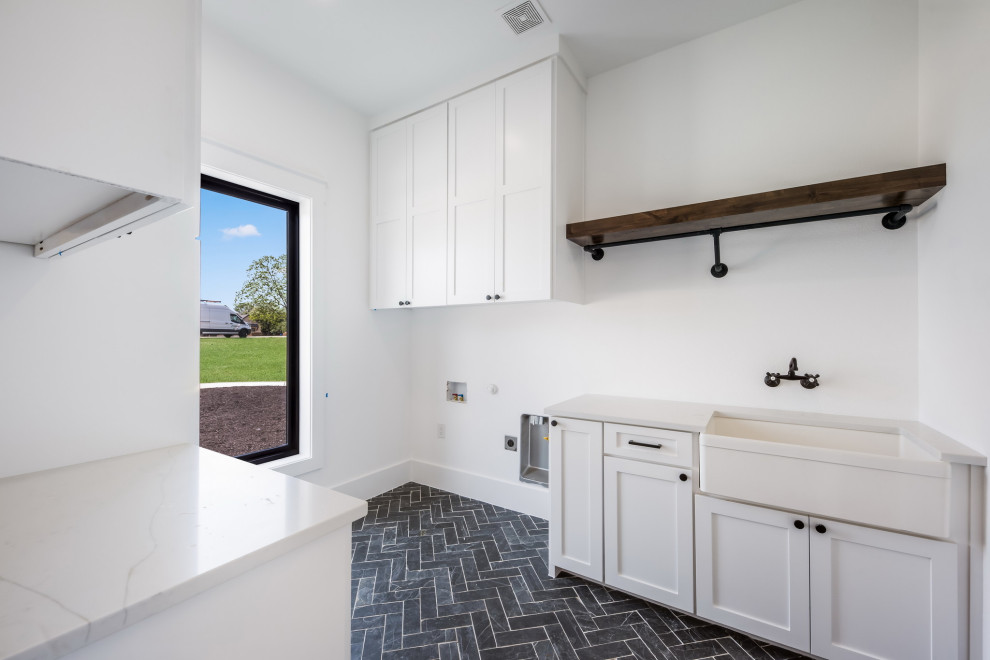 Inspiration for a large rural galley utility room in Dallas with an integrated sink, beaded cabinets, white cabinets, marble worktops, white walls, ceramic flooring, a side by side washer and dryer, black floors and white worktops.