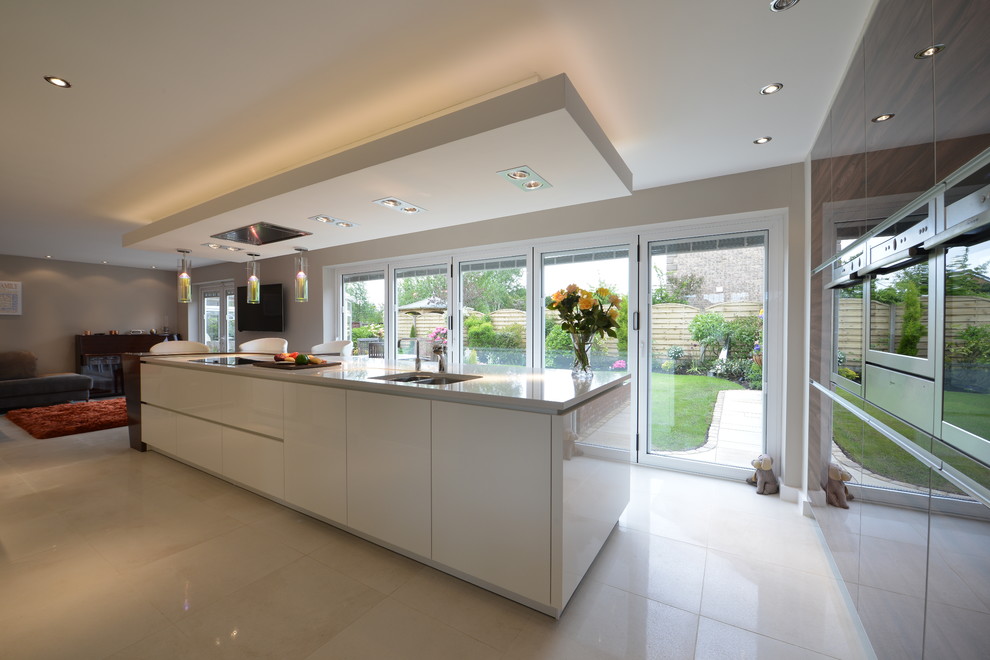 Inspiration for a modern kitchen in Manchester with a drop-in sink, flat-panel cabinets, white cabinets, solid surface benchtops, stainless steel appliances, porcelain floors and with island.