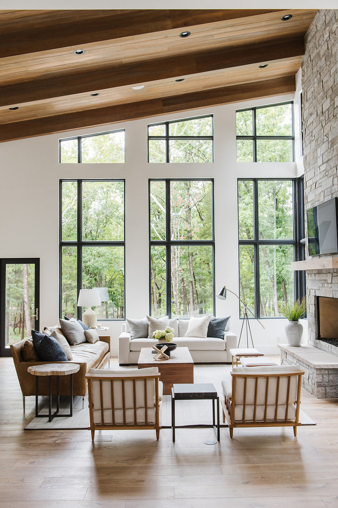 Inspiration for a large country open concept living room in Salt Lake City with white walls, light hardwood floors, a standard fireplace, a stone fireplace surround and a concealed tv.