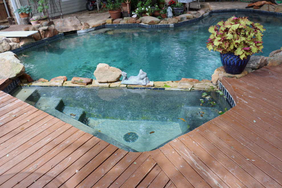 Design ideas for a traditional backyard custom-shaped pool in Dallas with a hot tub and decking.