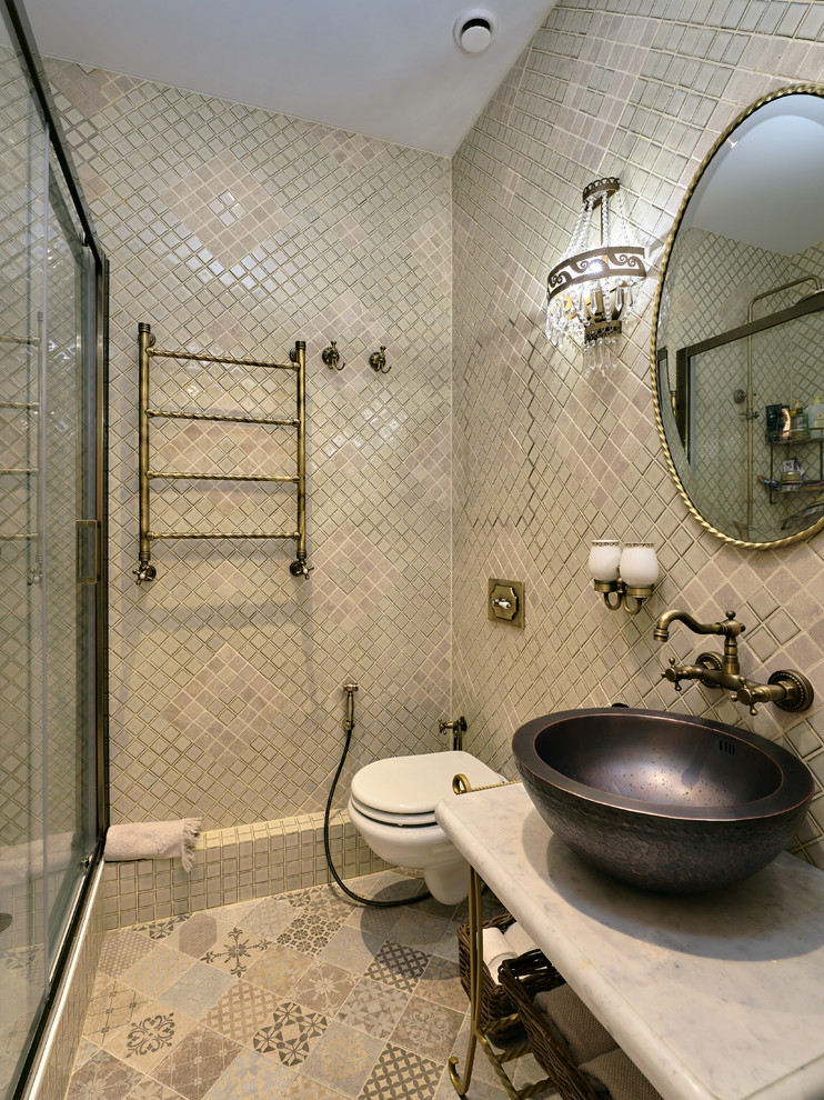 This is an example of a small traditional 3/4 bathroom in Moscow with an alcove shower, a wall-mount toilet, beige tile, travertine, porcelain floors, a vessel sink, marble benchtops, beige floor and a sliding shower screen.