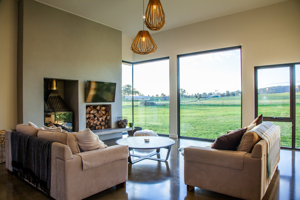 This is an example of a mid-sized contemporary open concept living room in Hobart with white walls, concrete floors, a concrete fireplace surround and a wall-mounted tv.