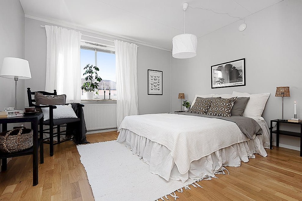 Scandinavian master bedroom in Stockholm with grey walls and light hardwood floors.