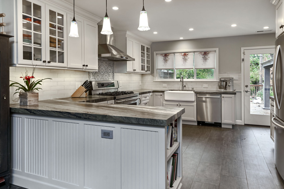 This is an example of a large transitional u-shaped eat-in kitchen in San Francisco with a farmhouse sink, recessed-panel cabinets, grey cabinets, quartzite benchtops, white splashback, ceramic splashback, stainless steel appliances, porcelain floors, a peninsula, grey floor and blue benchtop.