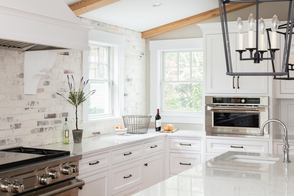 Inspiration for a large contemporary u-shaped medium tone wood floor and brown floor eat-in kitchen remodel in Boston with a farmhouse sink, shaker cabinets, white cabinets, marble countertops, white backsplash, brick backsplash, stainless steel appliances and an island