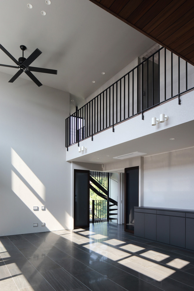 На фото: огромная гостиная-столовая в стиле модернизм с белыми стенами, полом из керамогранита, черным полом, потолком с обоями и панелями на стенах