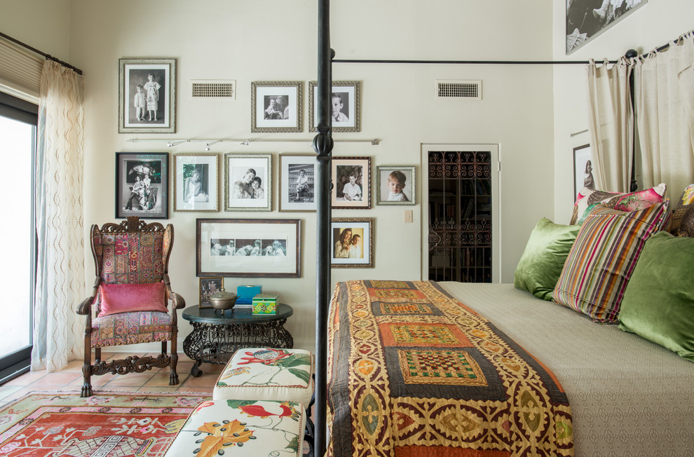 Large eclectic master bedroom in Other with beige walls and terra-cotta floors.