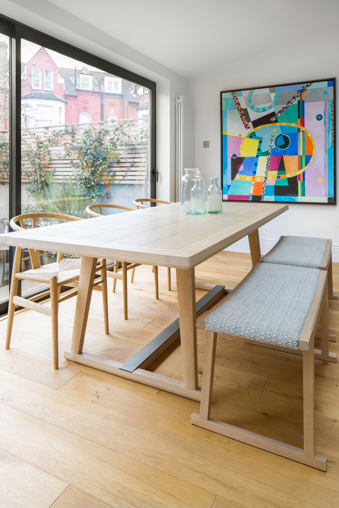 Photo of a mid-sized contemporary dining room in London with white walls, light hardwood floors, beige floor and no fireplace.