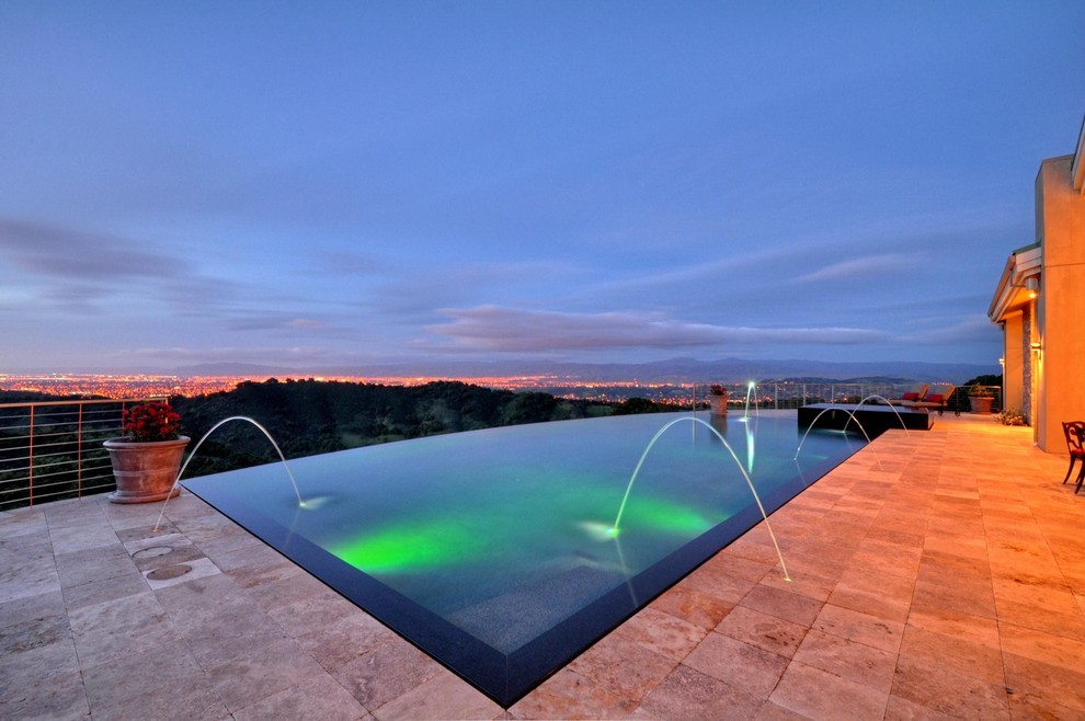 Mid-sized contemporary backyard rectangular infinity pool in San Francisco with a water feature and natural stone pavers.