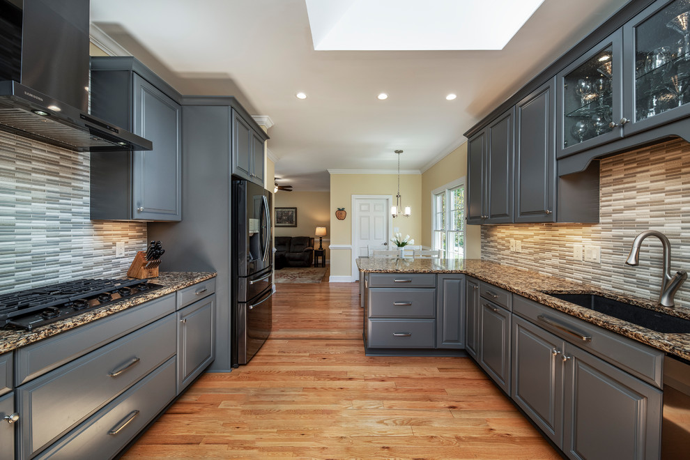 Inspiration for a transitional kitchen remodel with raised-panel cabinets, gray cabinets, granite countertops, black appliances, a peninsula and multicolored countertops