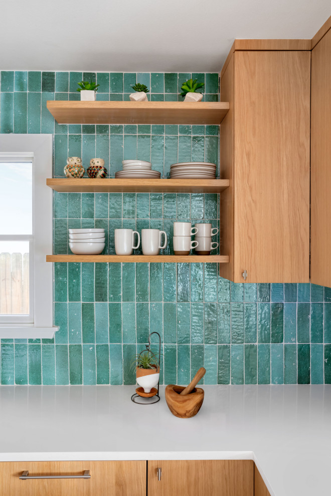 Inredning av ett modernt litet vit vitt kök, med en nedsänkt diskho, släta luckor, skåp i mellenmörkt trä, bänkskiva i glas, blått stänkskydd, stänkskydd i keramik, integrerade vitvaror, ljust trägolv, en köksö och brunt golv
