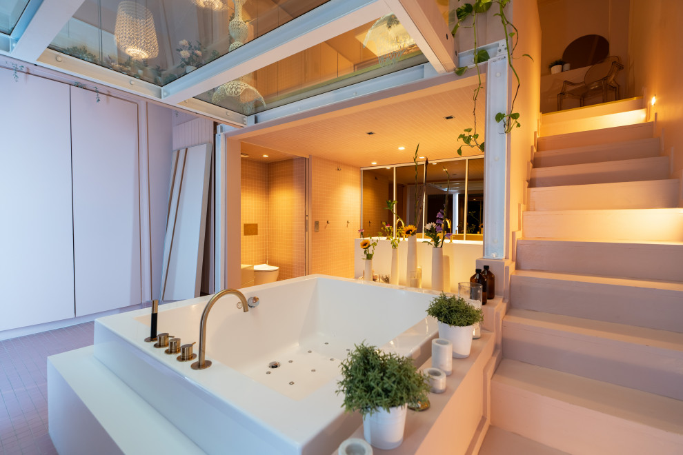 Expansive bohemian ensuite bathroom in Paris with beaded cabinets, a hot tub, an alcove shower, a wall mounted toilet, pink tiles, pink walls, an open shower, an enclosed toilet, double sinks and a built in vanity unit.
