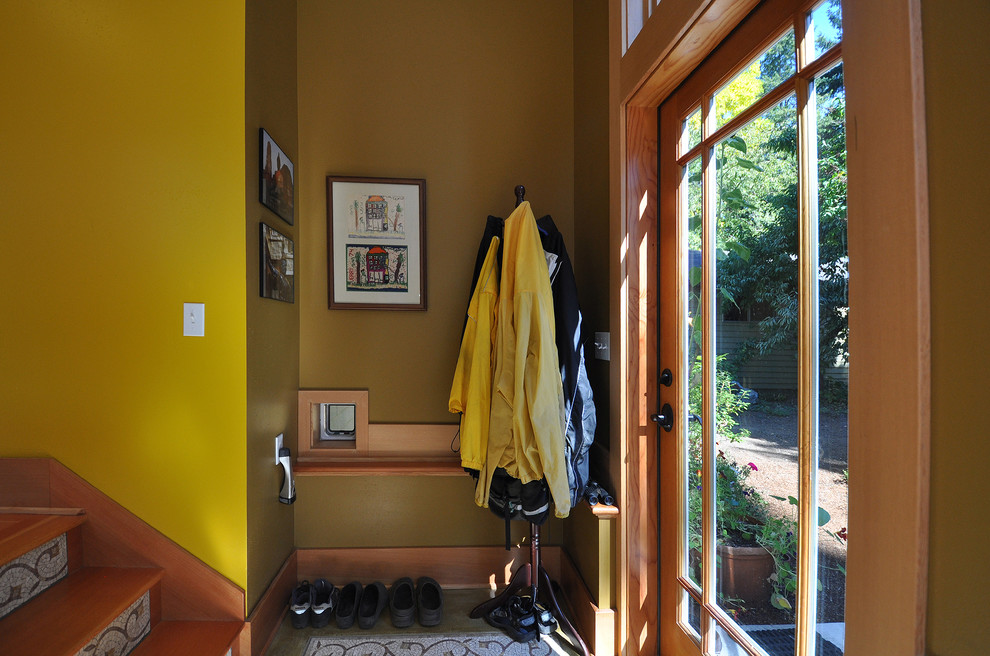 This is an example of a small arts and crafts vestibule in Seattle with green walls, concrete floors, a single front door and a light wood front door.