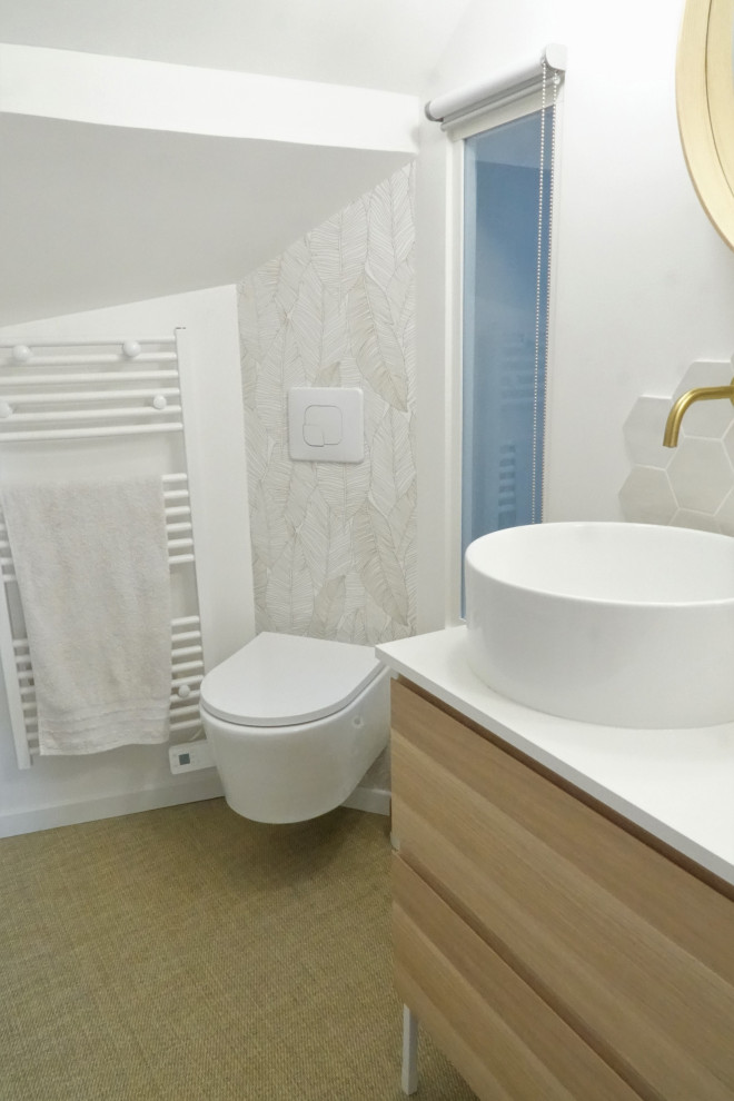 Photo of a small modern 3/4 bathroom in Other with beaded inset cabinets, light wood cabinets, a drop-in tub, a wall-mount toilet, white tile, porcelain tile, white walls, vinyl floors, a drop-in sink, laminate benchtops, beige floor, white benchtops, a single vanity, a freestanding vanity, exposed beam and wallpaper.