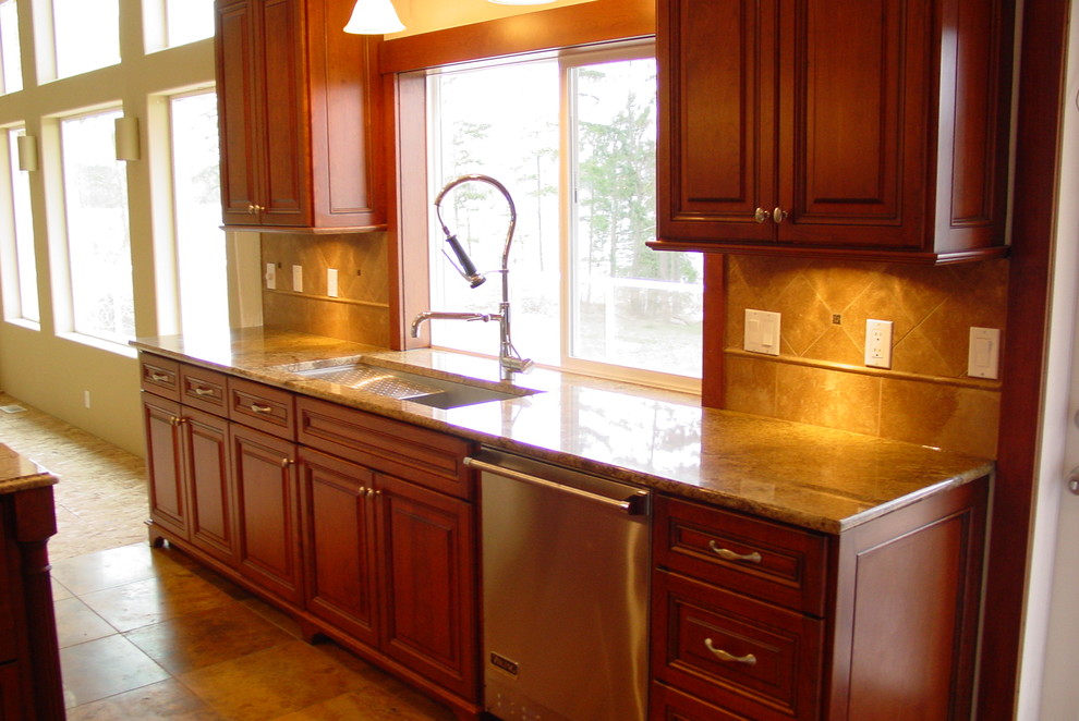 Large traditional u-shaped eat-in kitchen in Seattle with an undermount sink, raised-panel cabinets, medium wood cabinets, granite benchtops, beige splashback, ceramic splashback, stainless steel appliances, ceramic floors, with island and beige floor.