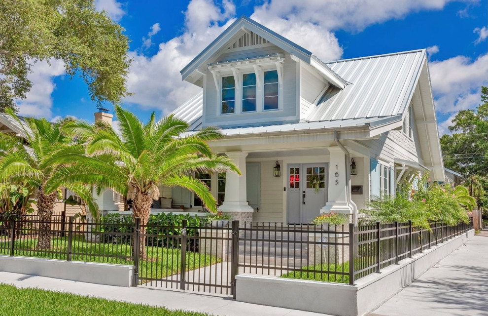 This is an example of an expansive beach style two-storey blue house exterior in Tampa with a mixed roof, a white roof, mixed siding and shingle siding.