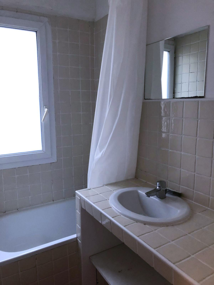 Пример оригинального дизайна: маленькая главная, серо-белая ванная комната в классическом стиле с серыми фасадами, душем без бортиков, инсталляцией, серой плиткой, белыми стенами, полом из плитки под дерево, консольной раковиной, столешницей из плитки, серым полом, душем с раздвижными дверями, белой столешницей, окном, тумбой под одну раковину и подвесной тумбой для на участке и в саду
